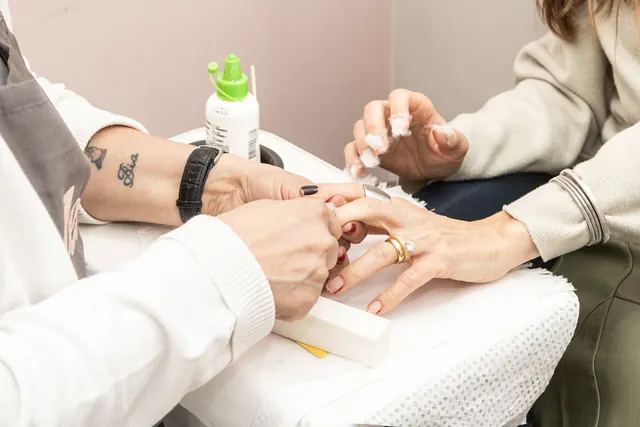 Manicure da Less lixando as unhas de uma cliente